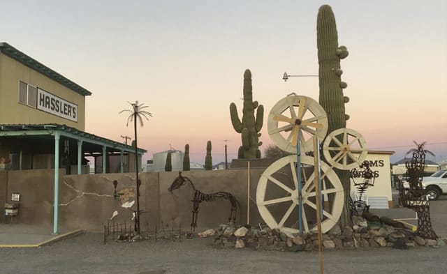 Wagon wheels and metal cactus sculptures along the park at dusk