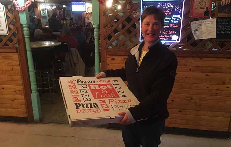 A guest holding a pizza box at Silly Al's Pizza